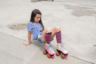 a little girl sitting on a skateboard with her feet on the ground