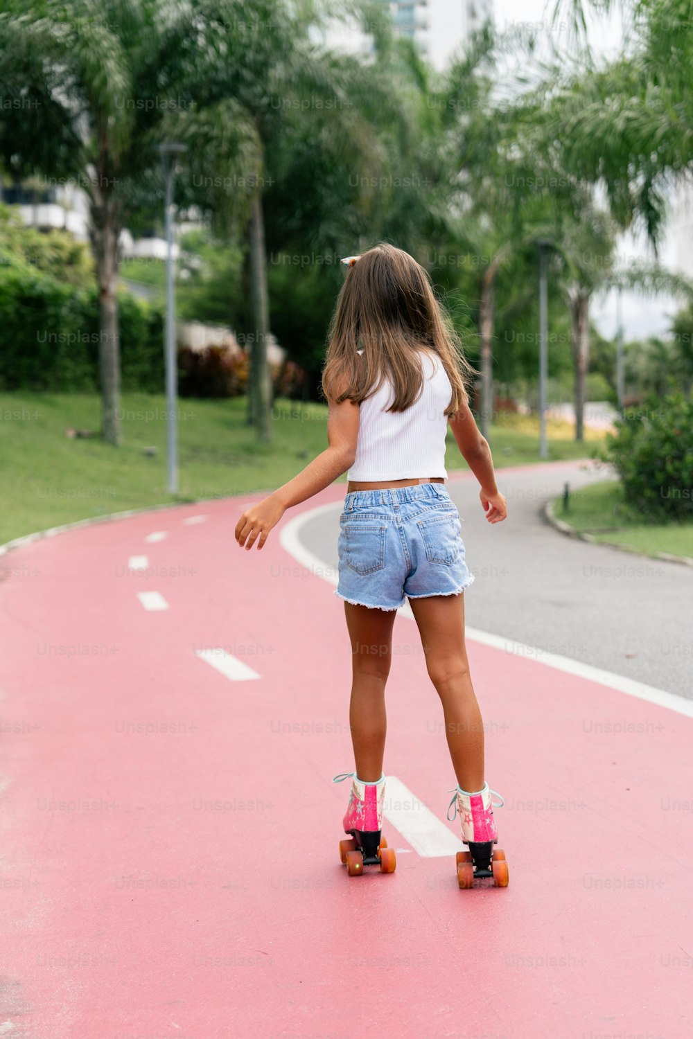 a little girl riding a skateboard down a pink road