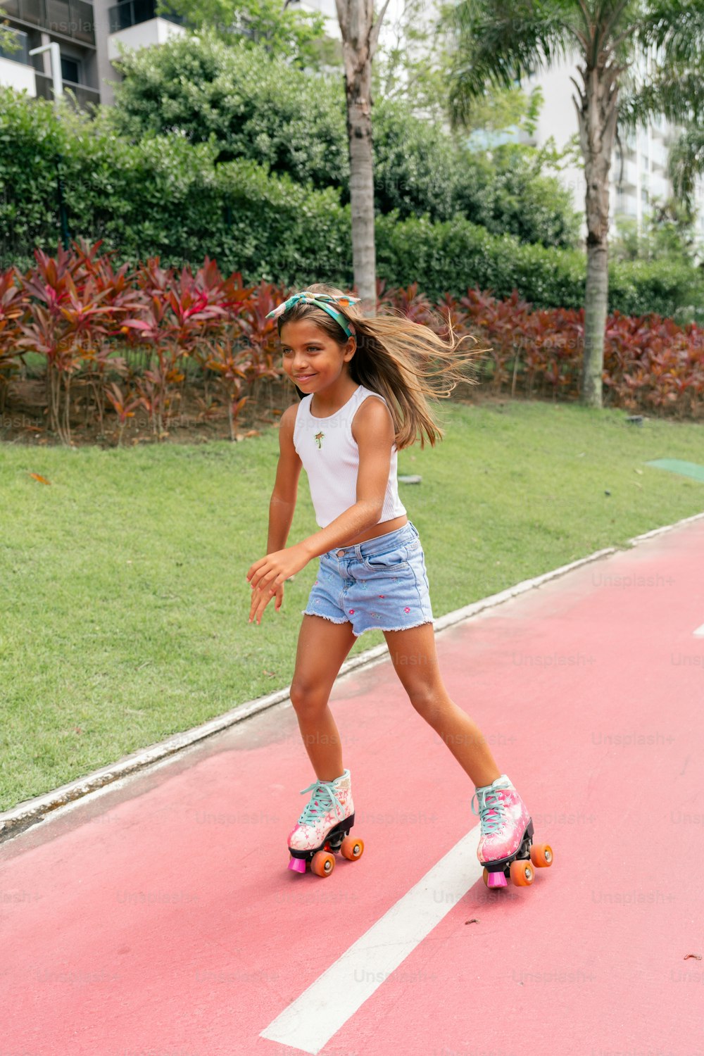 a young girl riding a skateboard on a pink surface