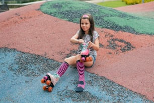 a little girl sitting on the ground with her skateboard
