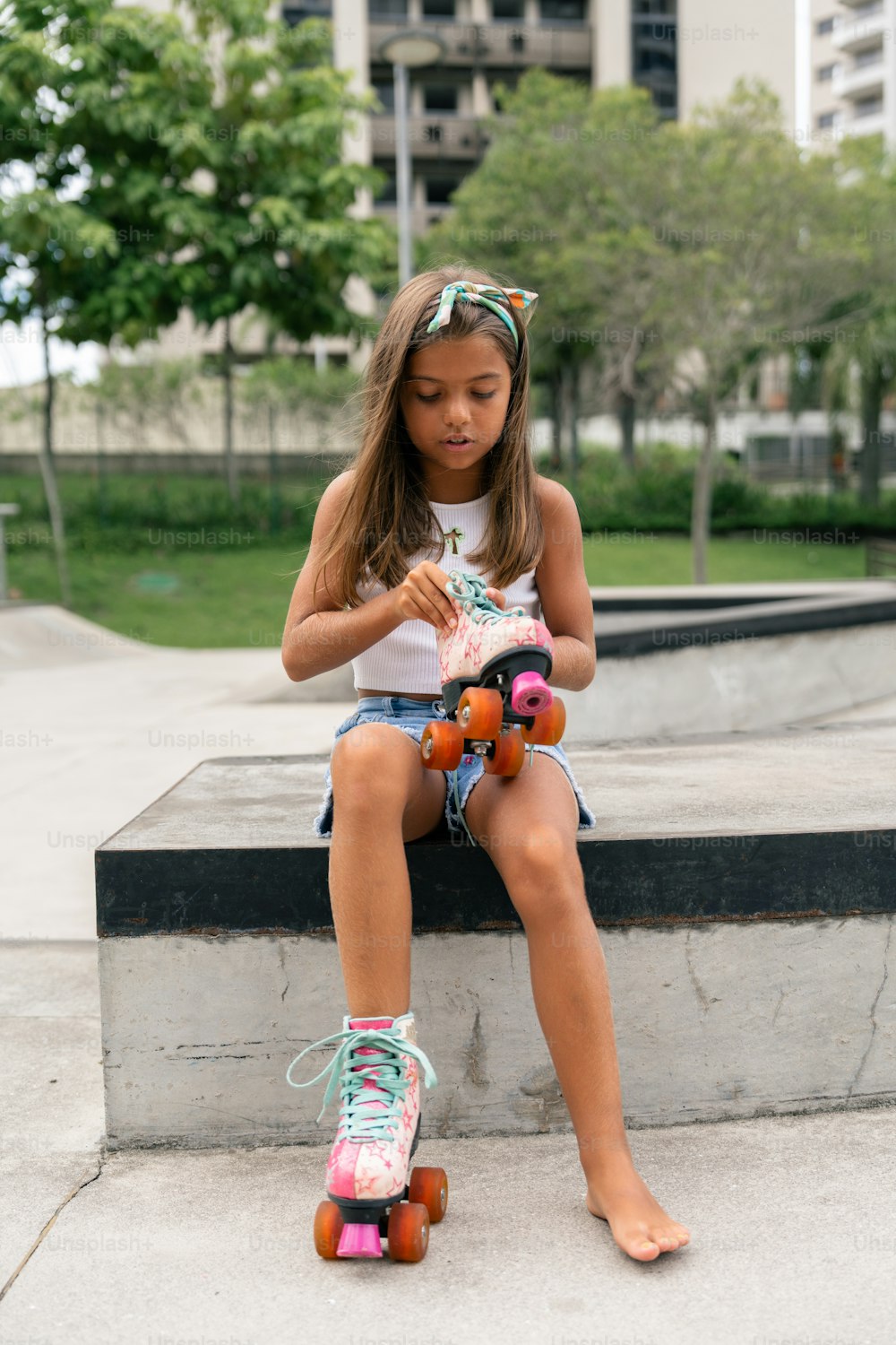 a little girl sitting on a ledge with a skateboard