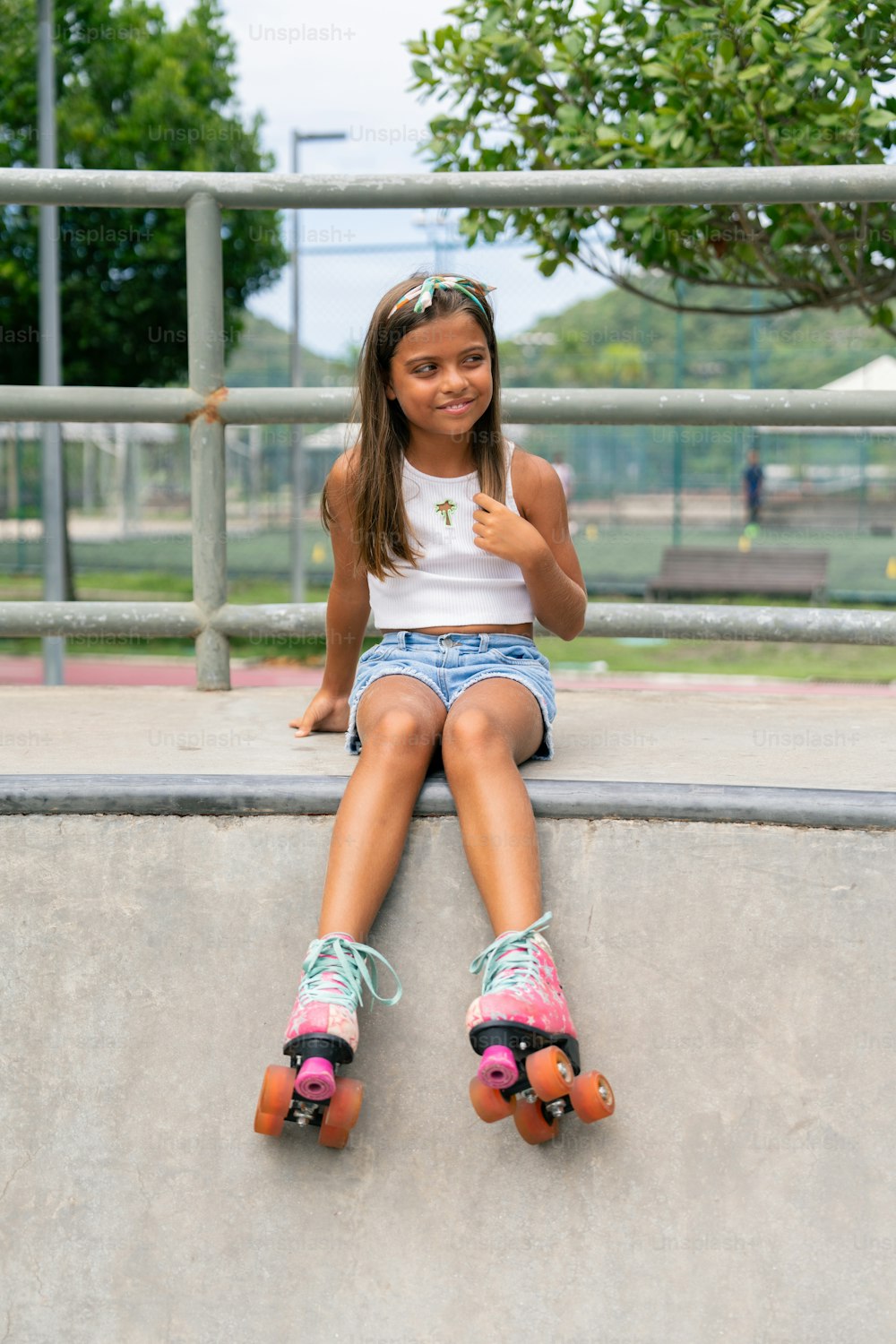 a young girl sitting on top of a skateboard ramp