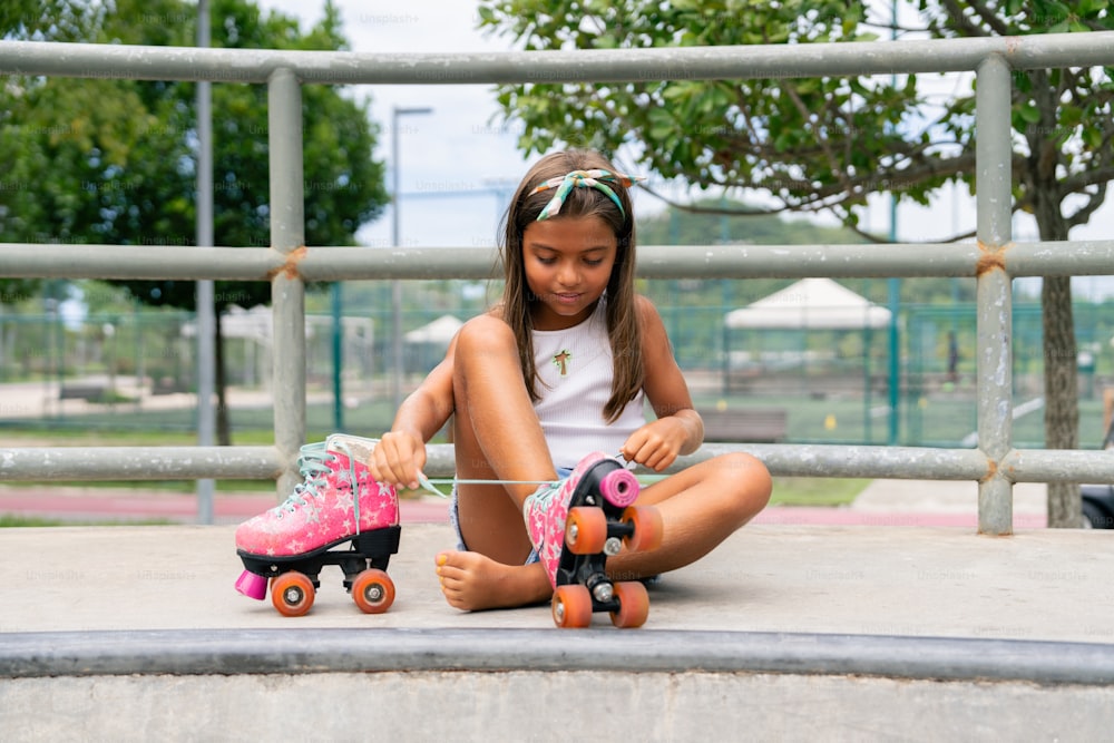 una bambina seduta a terra con il suo skateboard