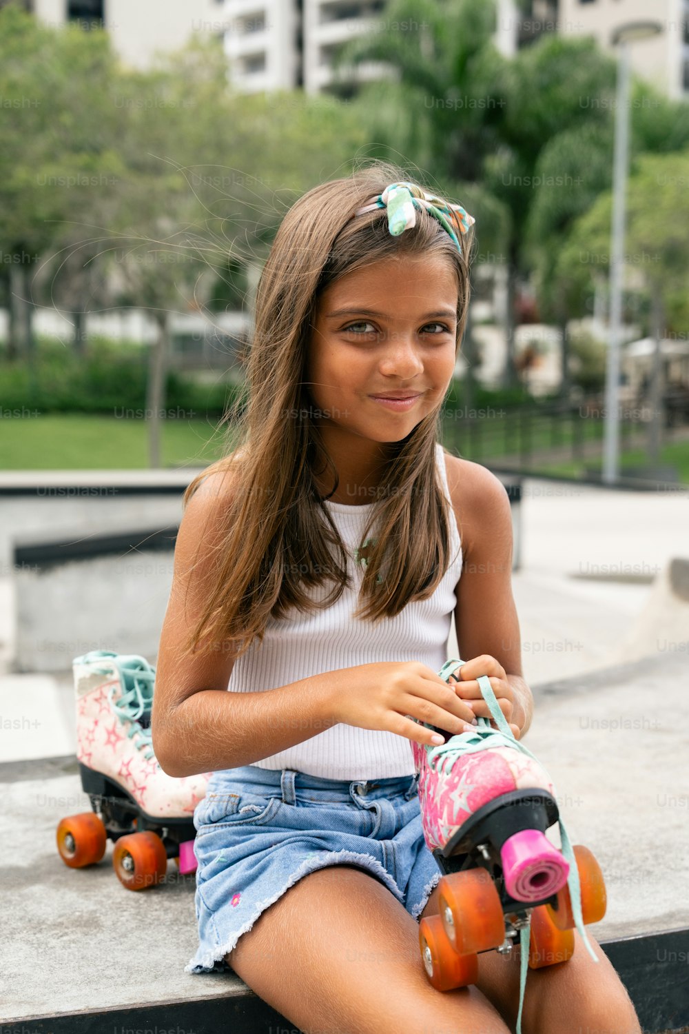 a young girl sitting on a ledge with her skateboard