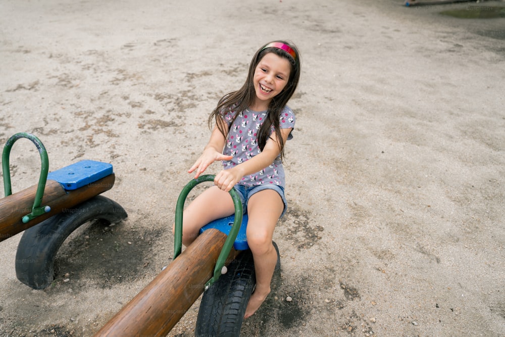 una niña sentada encima de una bicicleta de madera