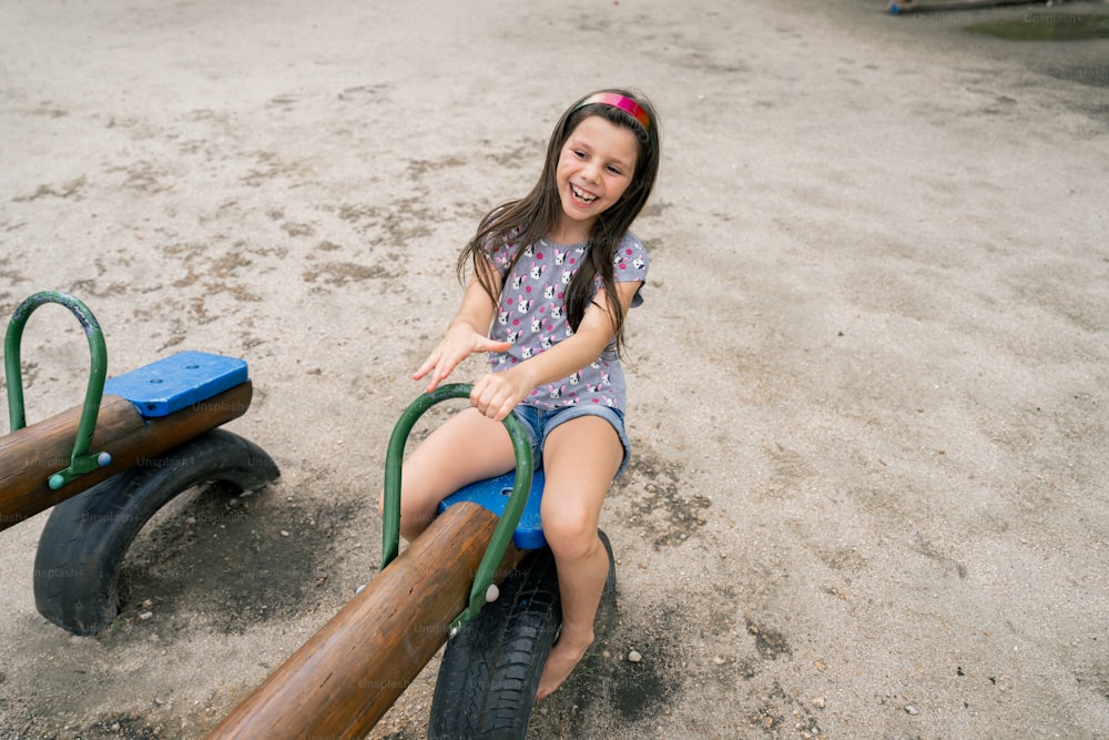 a little girl sitting on top of a wooden bike