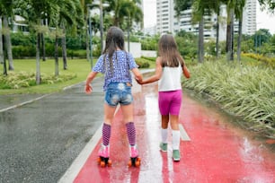 two little girls walking down the street in the rain
