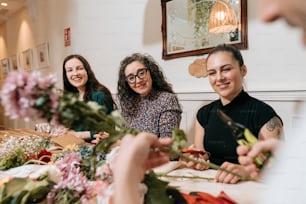 a group of women sitting around a table cutting flowers