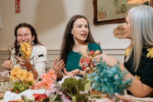 a group of women sitting around a table with flowers