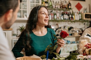 a woman sitting at a table with a rose in her hand