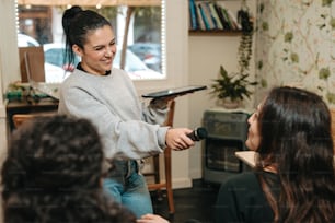 a woman holding a hairdryer in front of a group of women