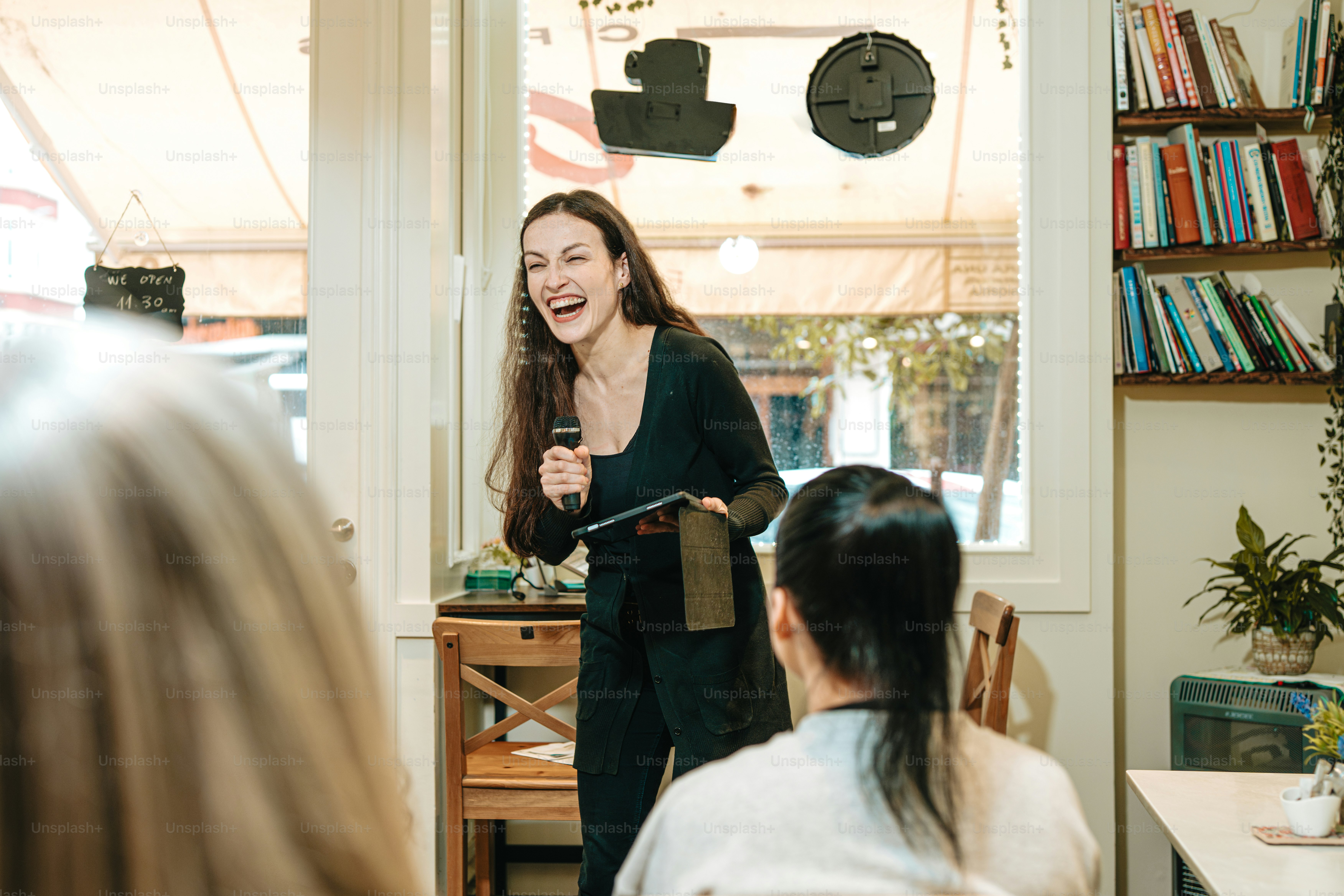 a woman standing in front of a table holding a microphone