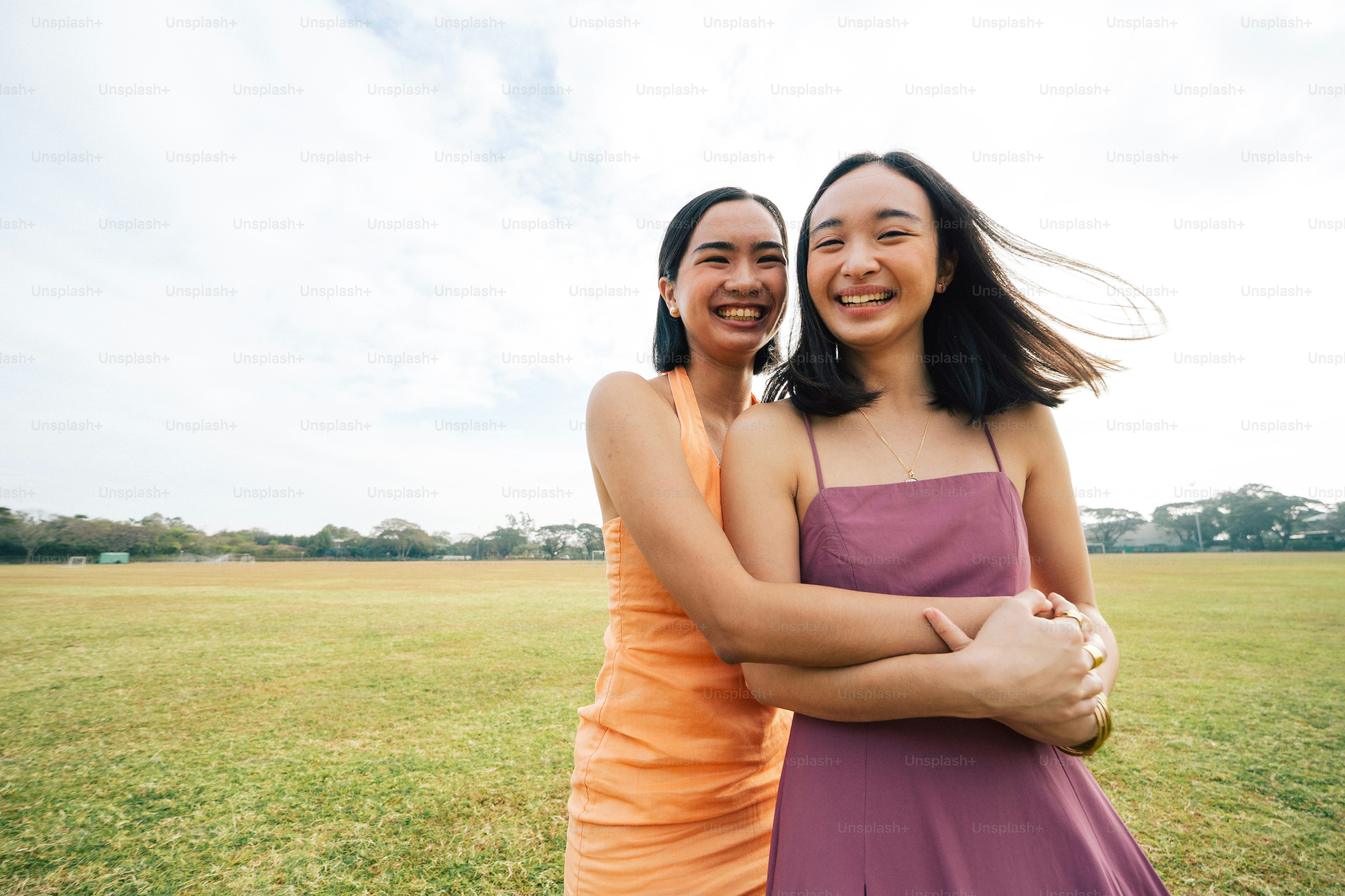 two young women standing next to each other in a field