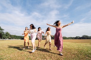 a group of women running across a grass covered field