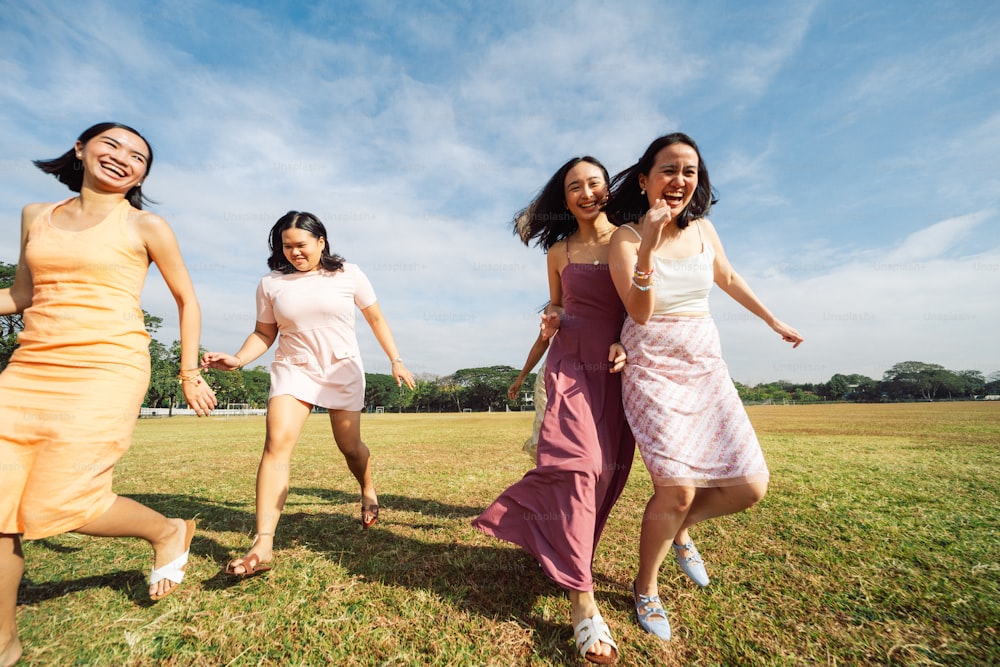 a group of young women running across a grass covered field