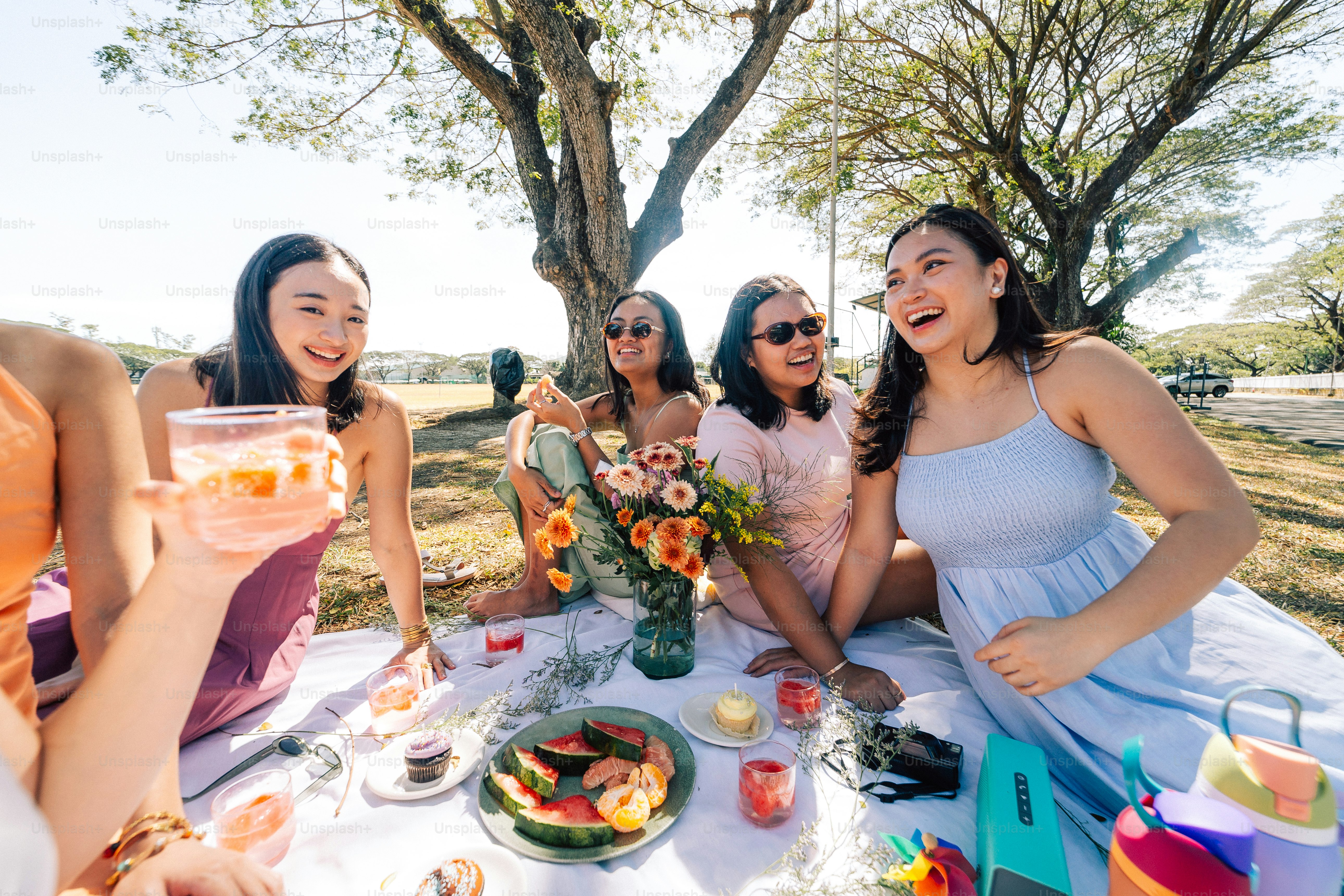 a group of women sitting around a table with food and drinks