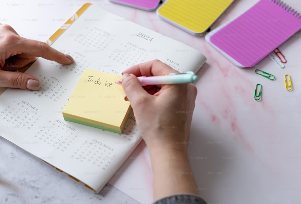 a person writing on a notepad with a pen