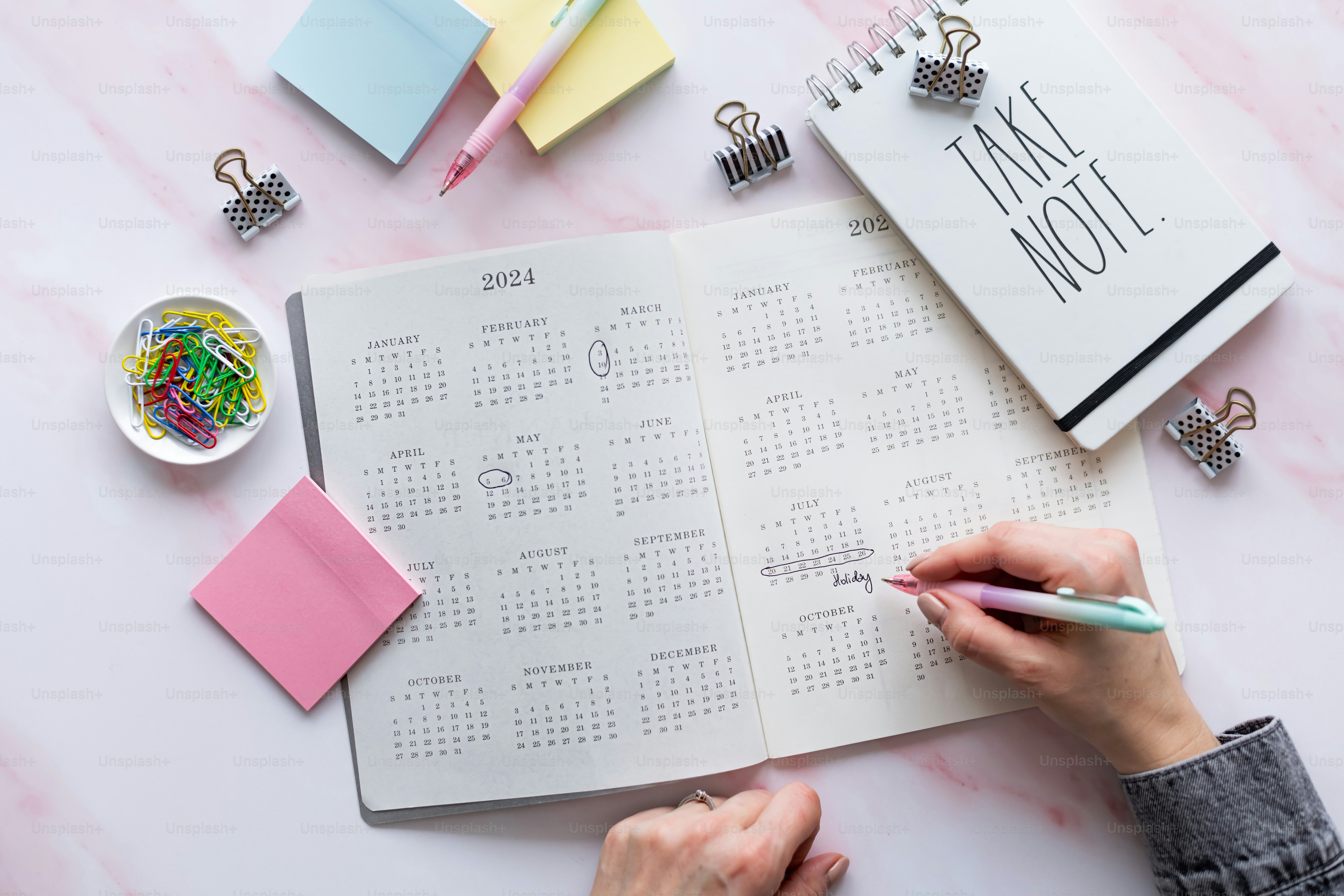 a person writing on a planner next to a cup of coffee