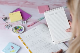 a woman is looking at a planner on a desk