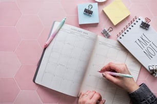 a person is writing on a calendar with a pen