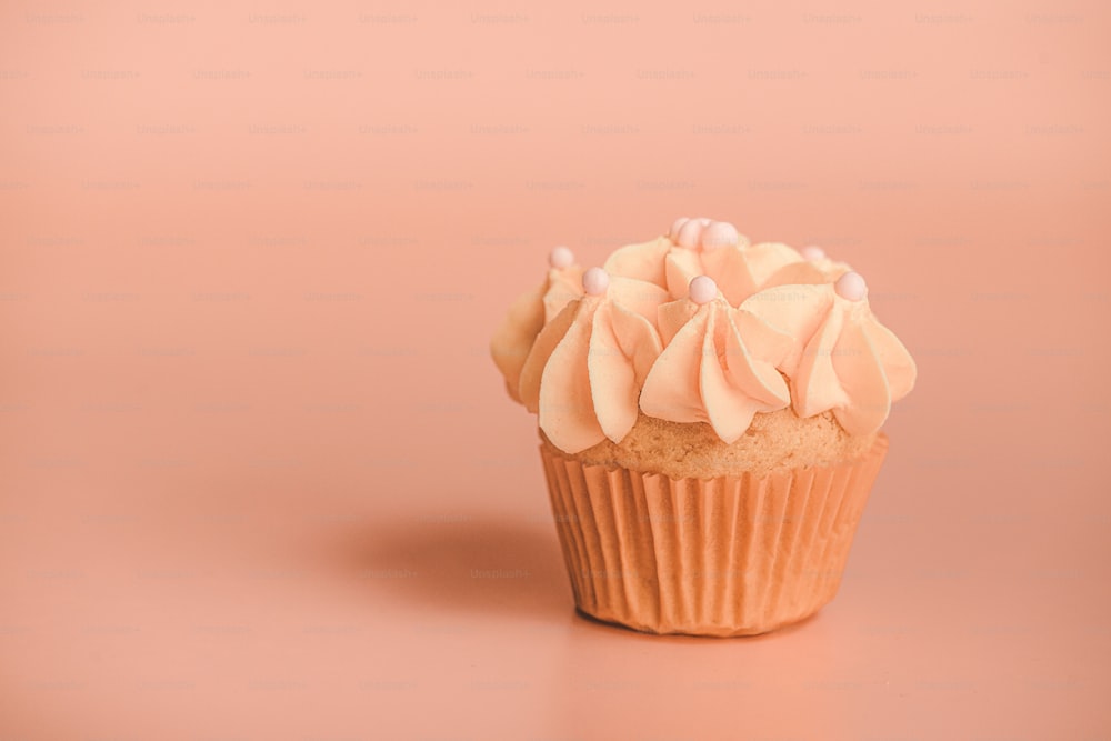 a cupcake with frosting on a pink background