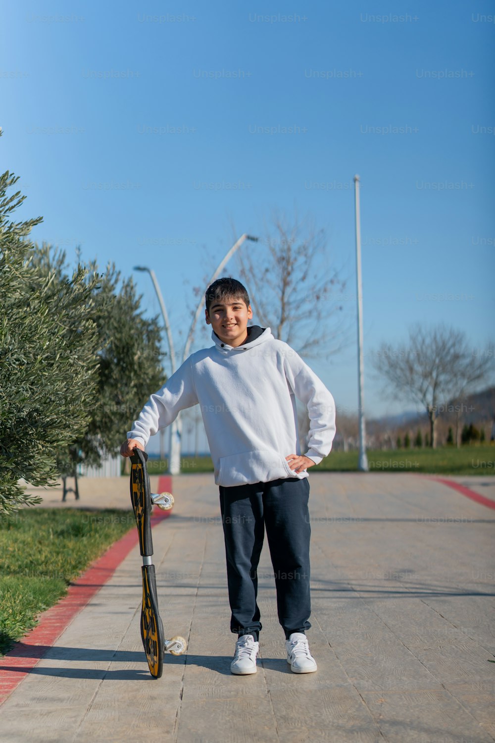 a young man standing on a sidewalk holding a skateboard