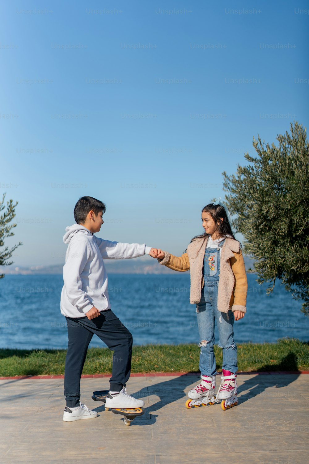 a boy and a girl on a skateboard near the water