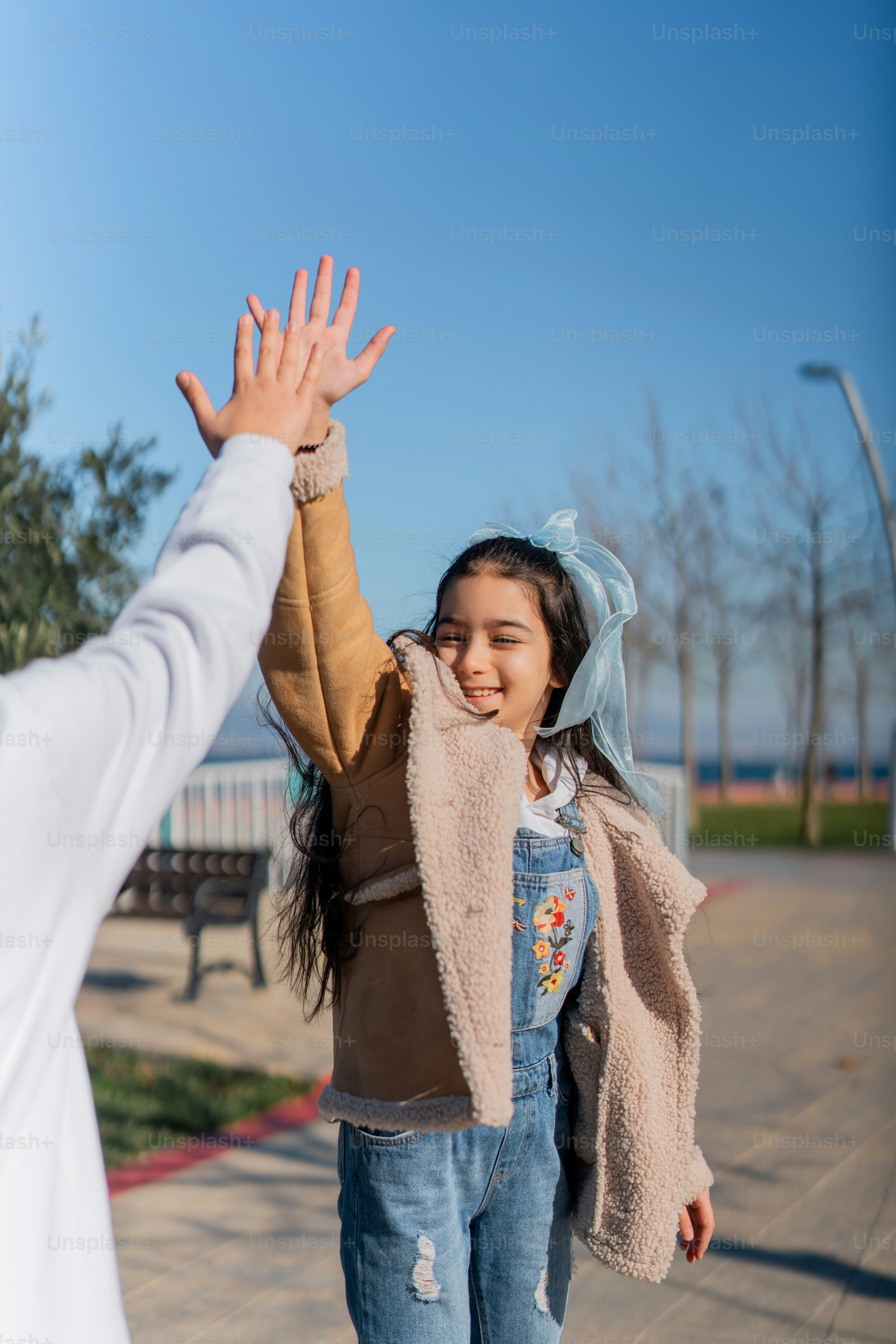 a little girl is holding her hands up in the air