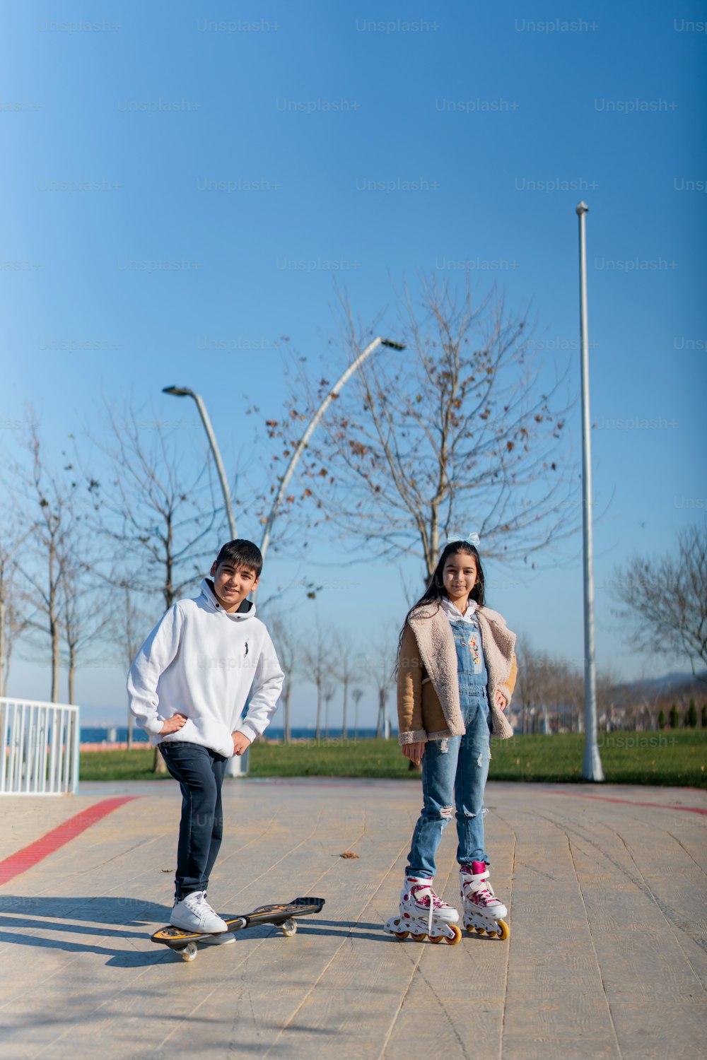 a boy and a girl riding skateboards in a park