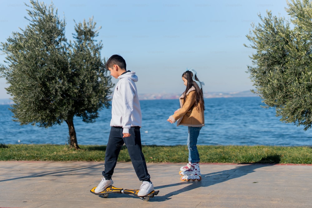 a boy and a girl are skateboarding by the water