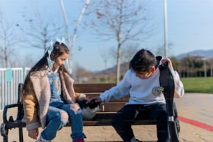 a boy and a girl sitting on a bench