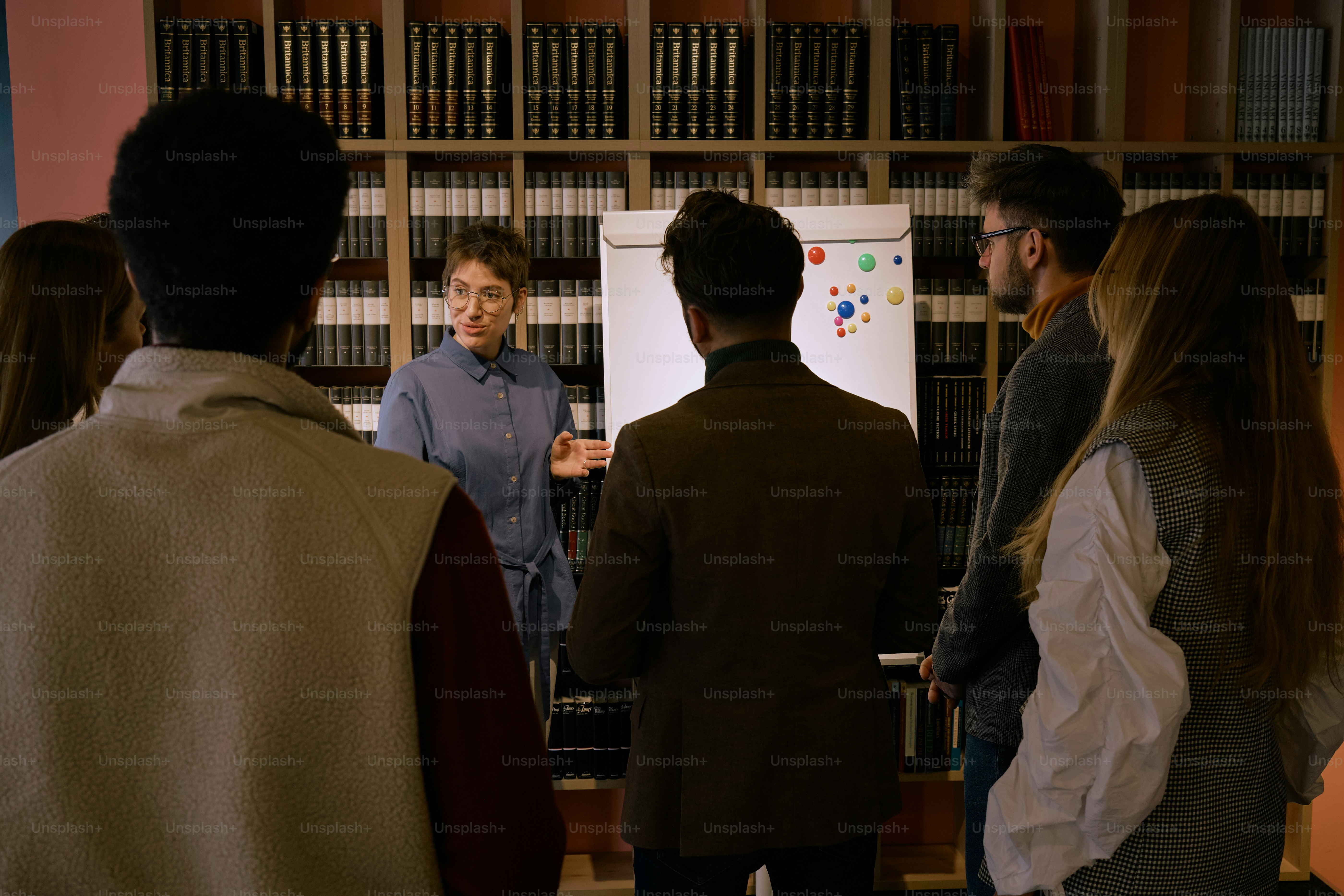 a group of people standing around a white board