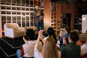 a man standing on top of a chair in front of a group of people