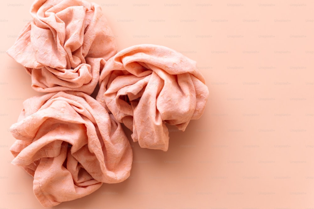 three pieces of pink fabric on a pink background