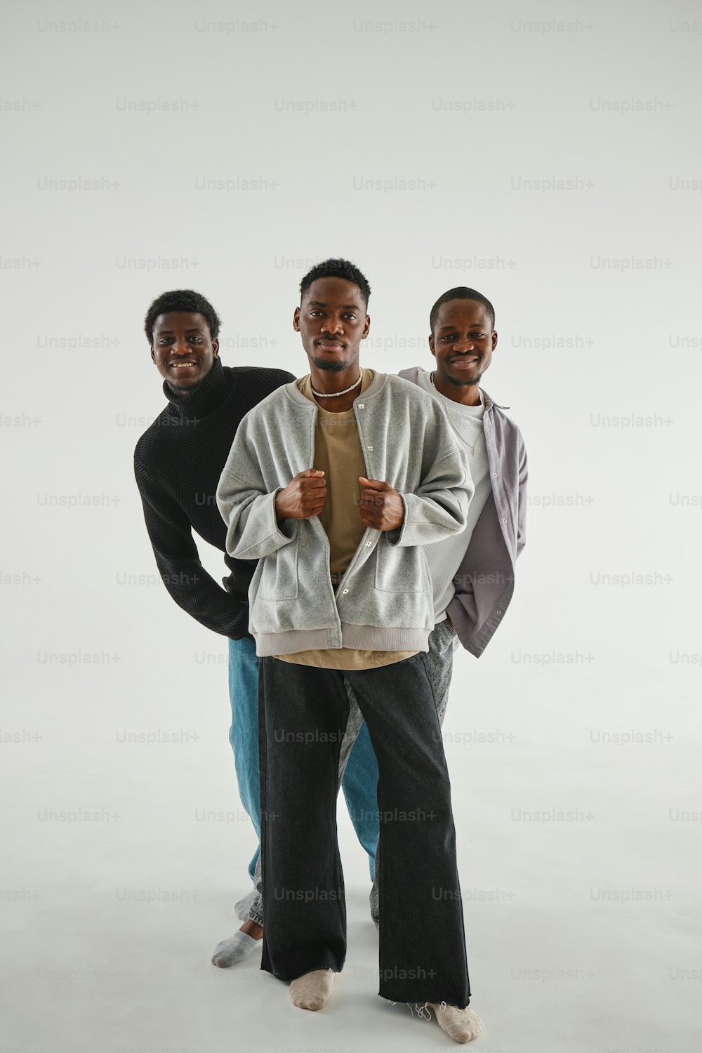 three men standing next to each other in front of a white background
