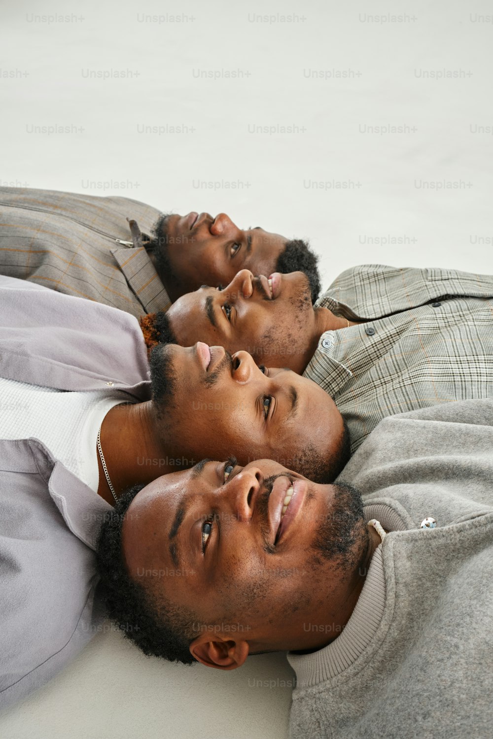three men laying on a bed looking up