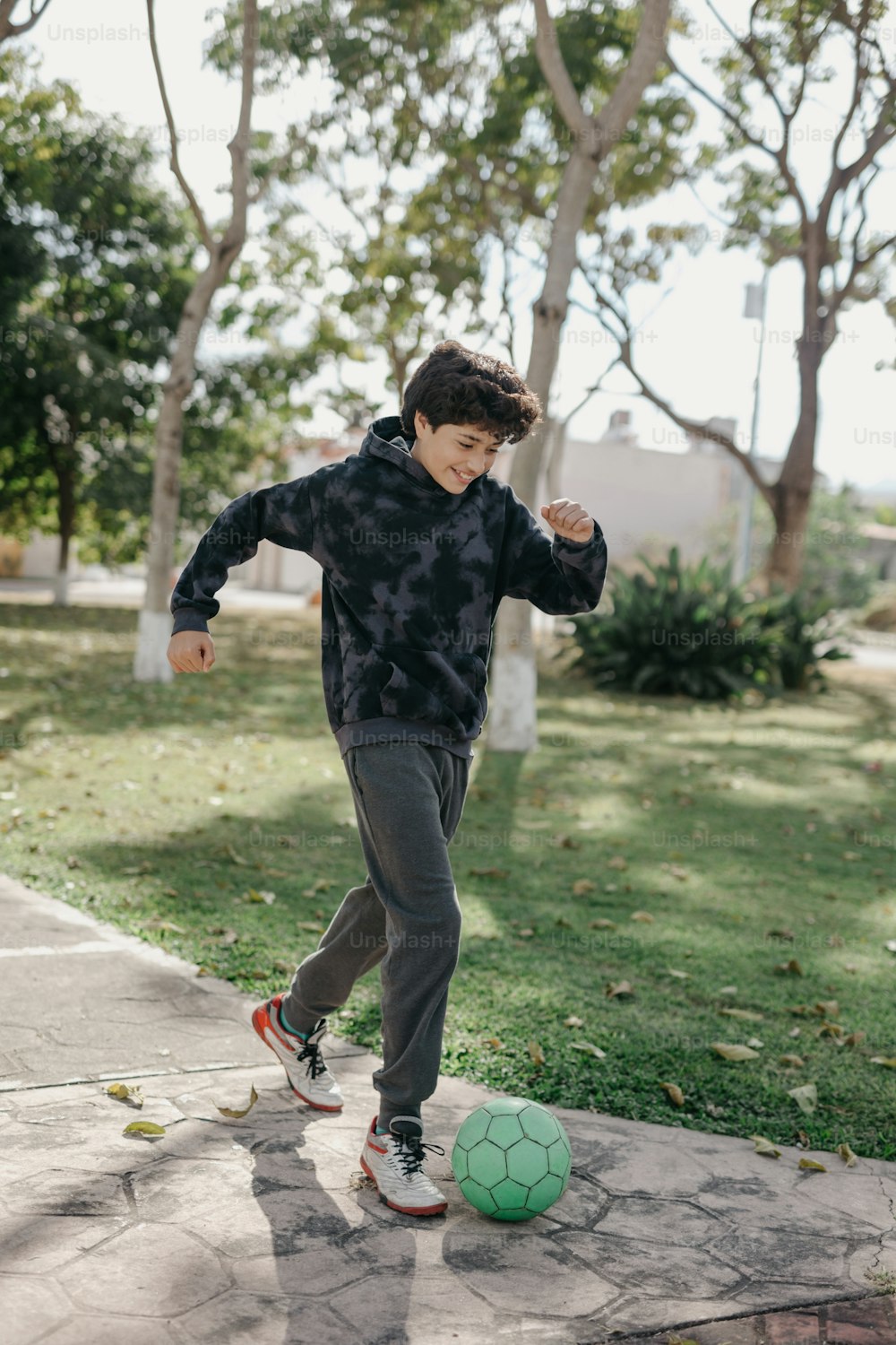 Ein kleiner Junge kickt einen Fußball auf einem Bürgersteig