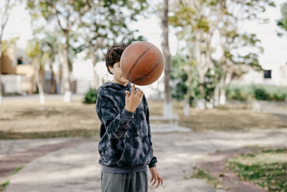 un ragazzino che tiene un pallone da basket in faccia