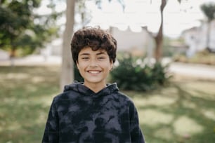 a young boy smiling at the camera in a park