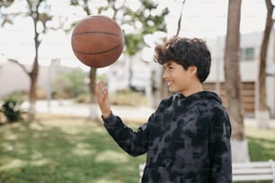 a young boy is spinning a basketball on his finger
