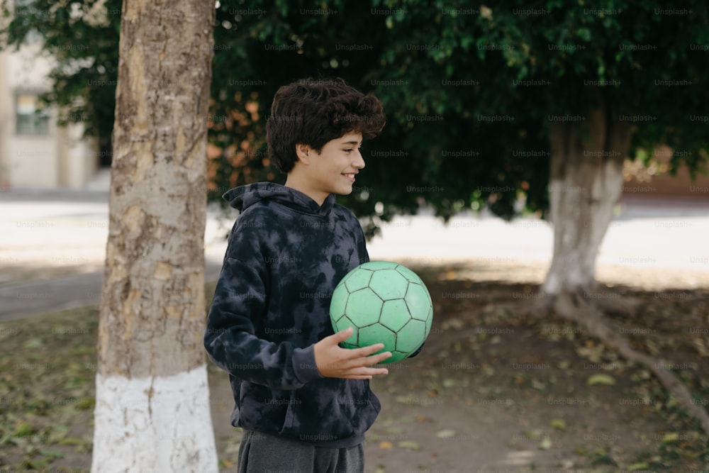 a young boy holding a green soccer ball