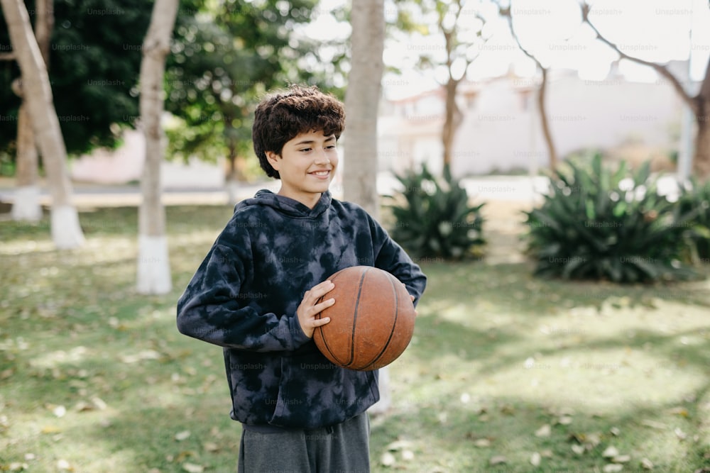 un niño sosteniendo una pelota de baloncesto en un parque