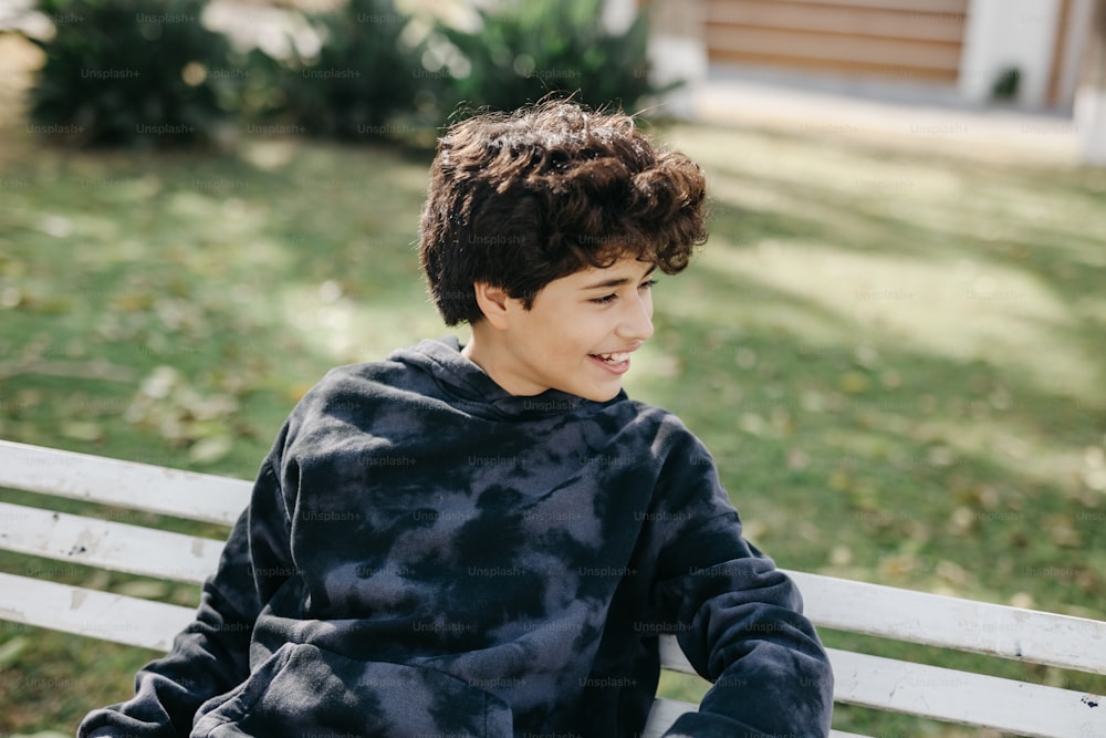 a young boy sitting on a white bench