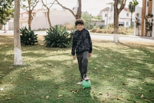 a young boy standing on top of a green soccer ball