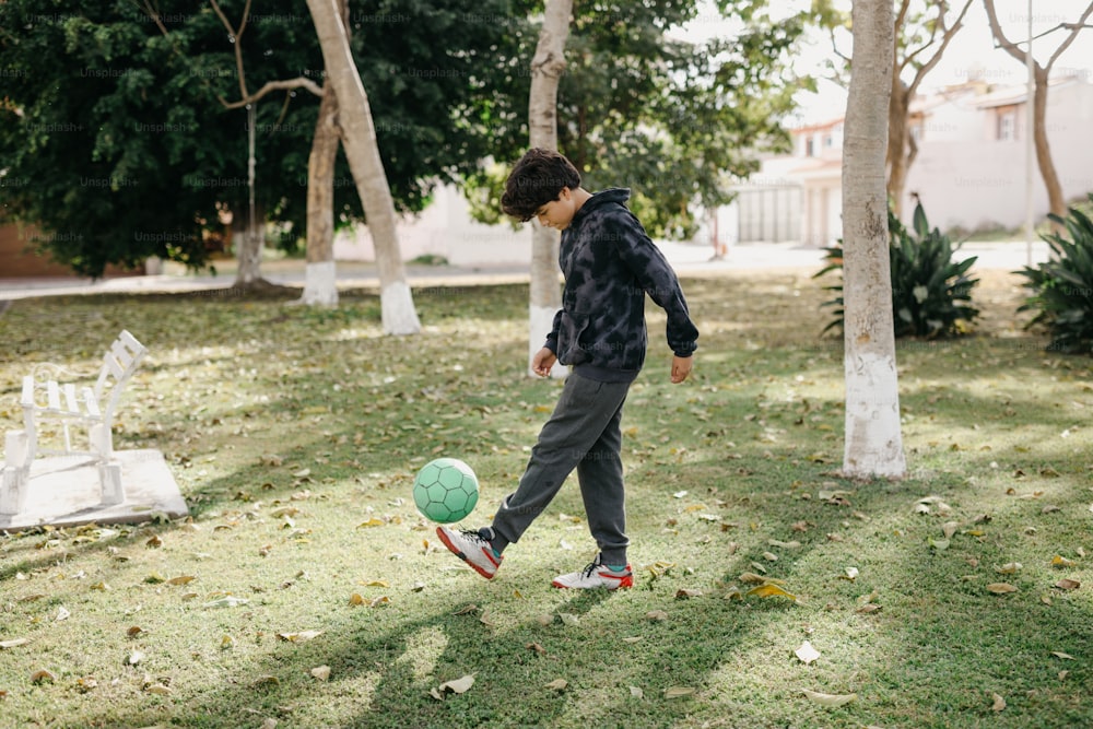 a young man kicking a soccer ball in a yard