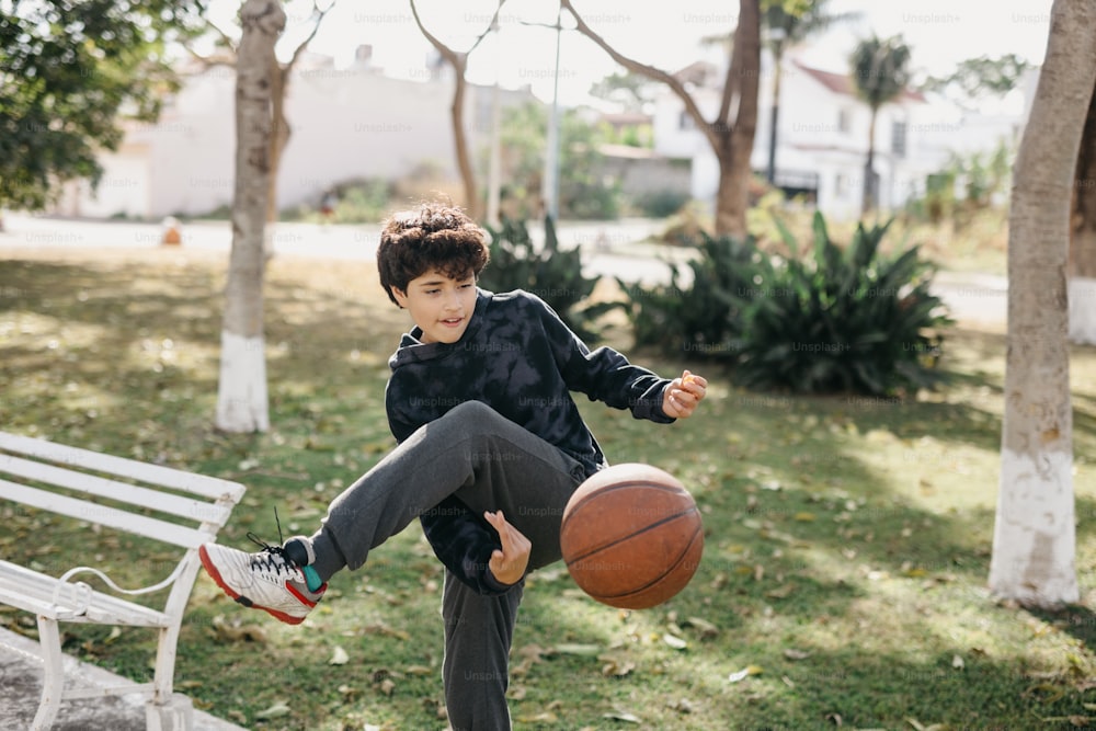 a young boy holding a basketball while sitting on a bench