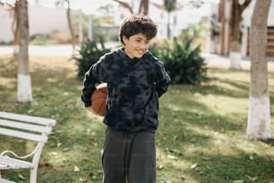 a young man holding a basketball standing next to a bench