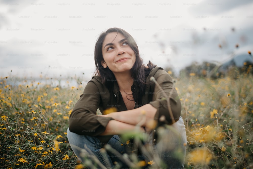 una mujer sentada en un campo de flores amarillas