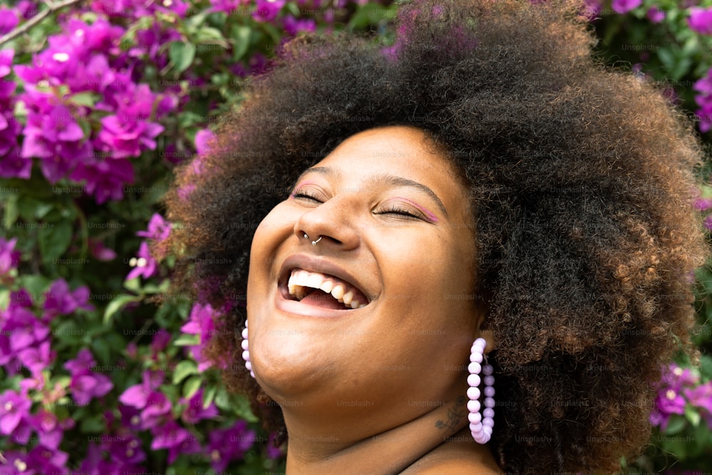 uma mulher rindo na frente de flores roxas