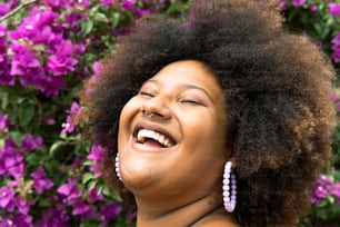 a woman laughing in front of purple flowers
